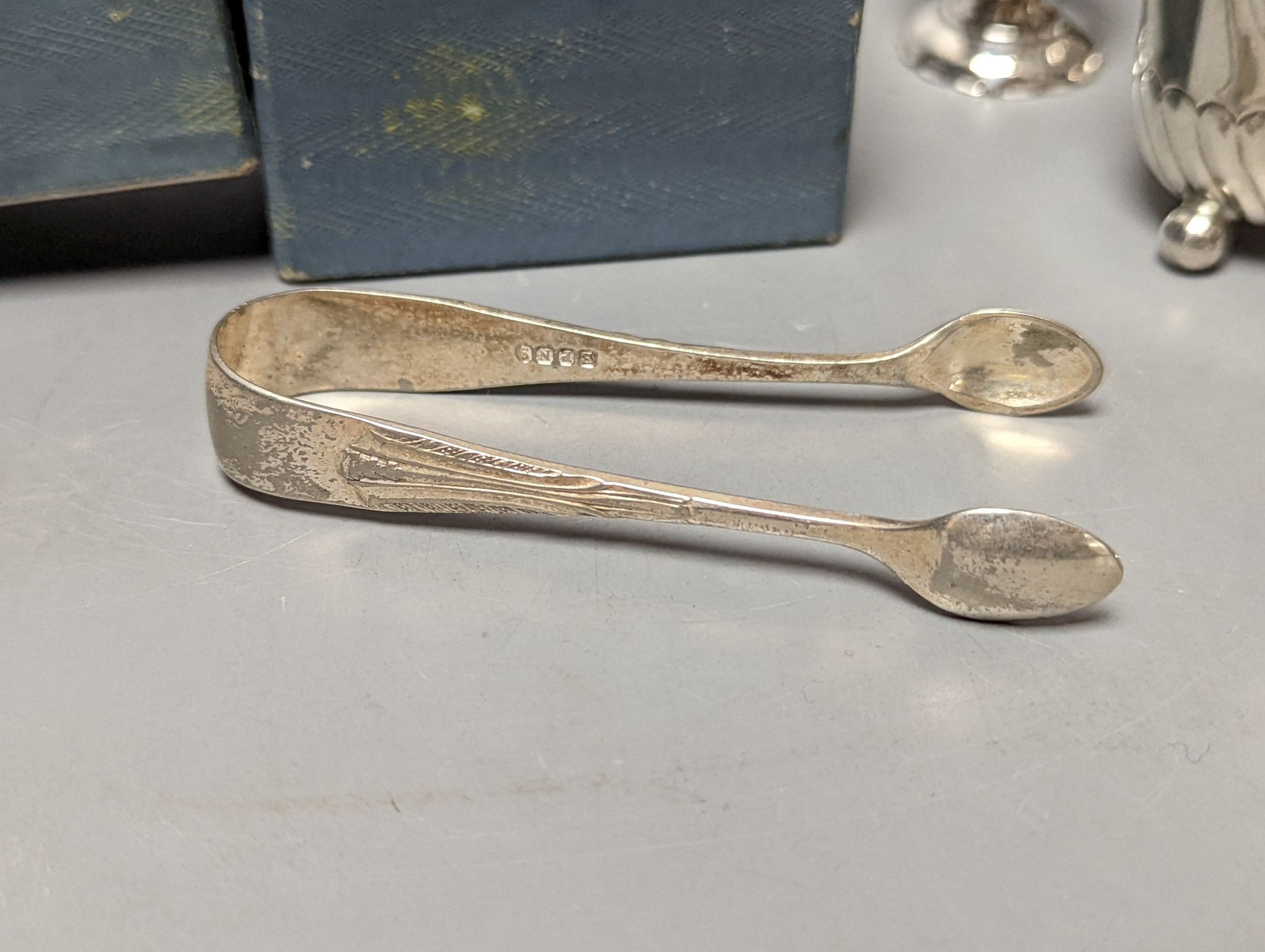 A cased silver napkin ring, seven assorted silver pepperettes including Guernsey can and a pair of plated sugar tongs.